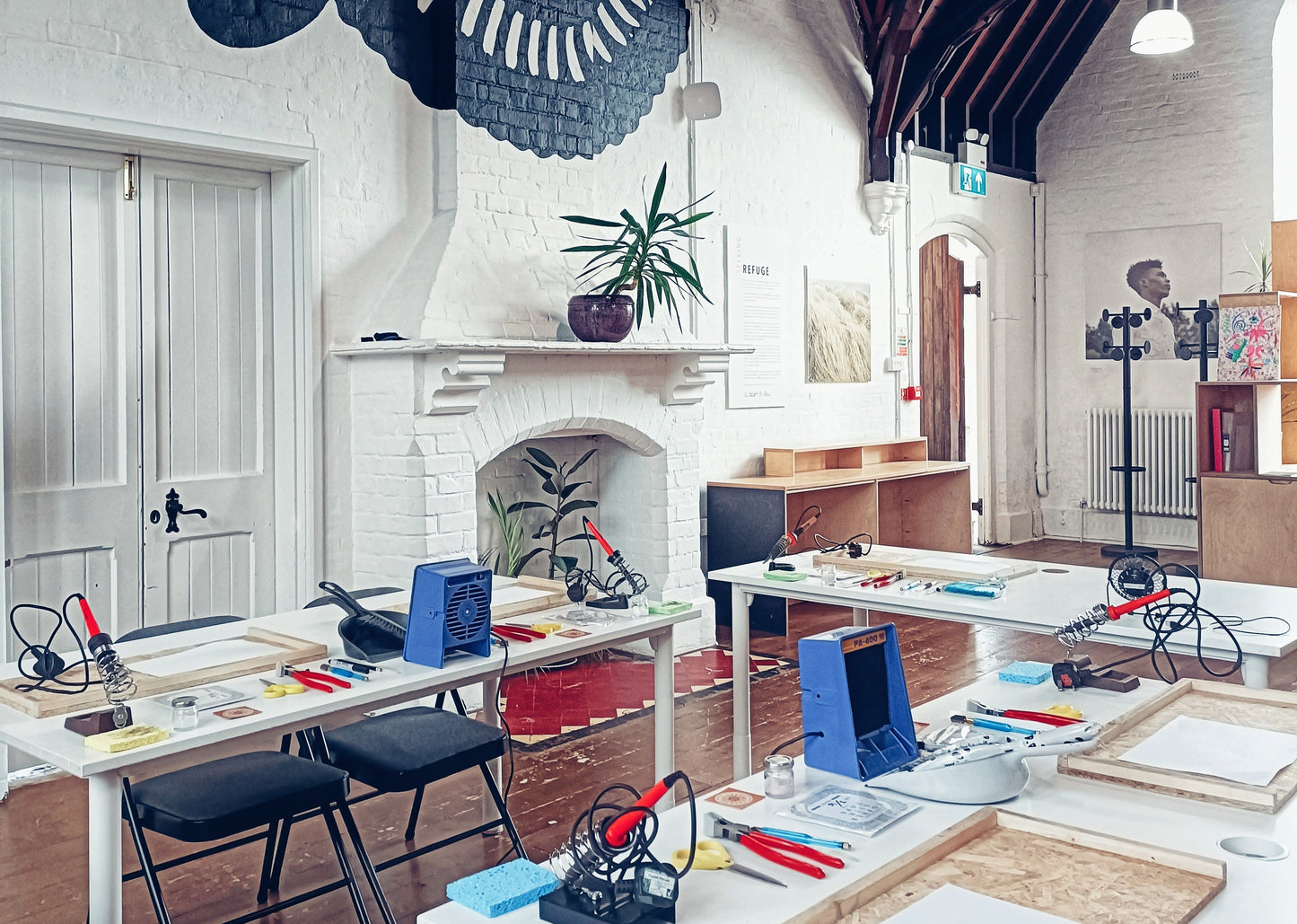 Creative workspace in Bournemouth set up for a stained glass workshop with tables, chairs, and various tools in a grade 2 listed building with wooden beams.